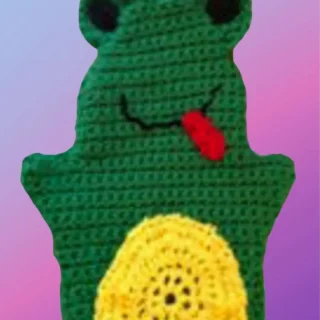 Green crocheted frog hand puppet with black eyes, smiling mouth and yellow belly