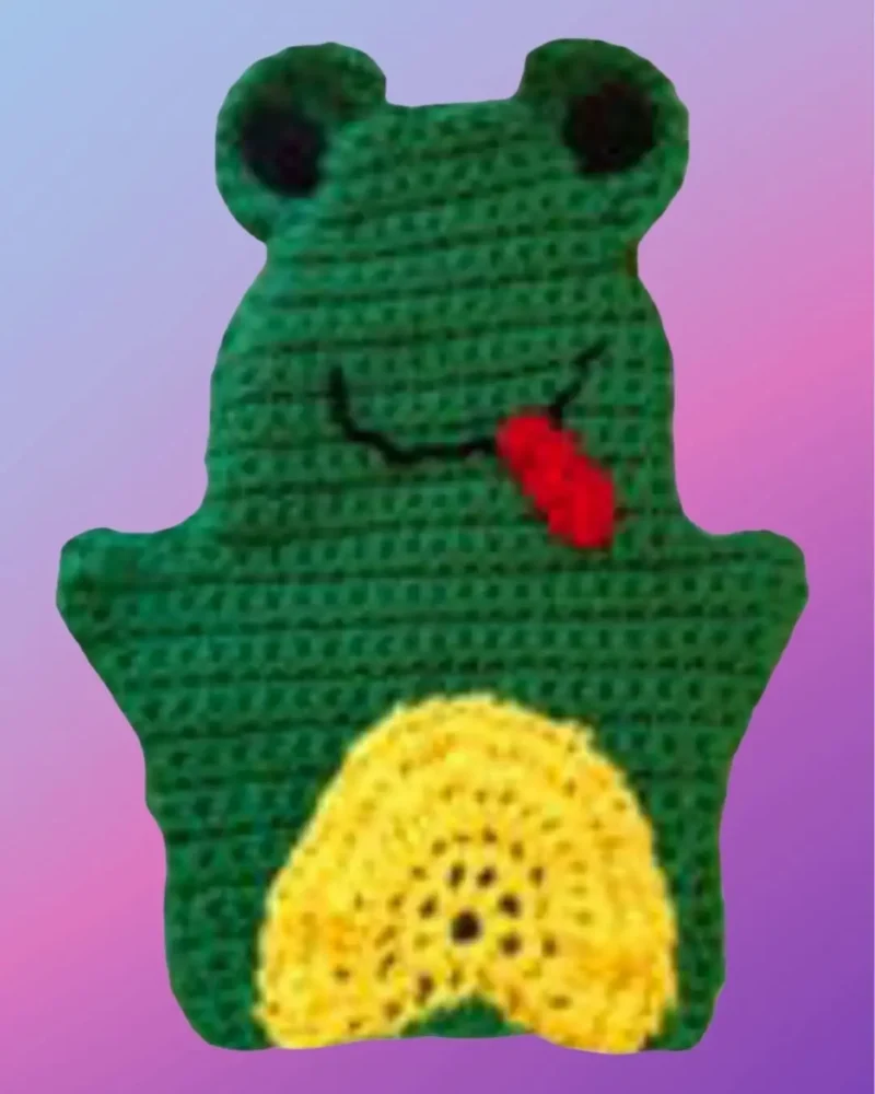 Green crocheted frog hand puppet with black eyes, smiling mouth and yellow belly