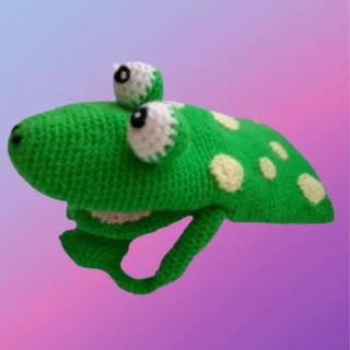 Green crocheted frog hand puppet with large raised eyes and cream spots