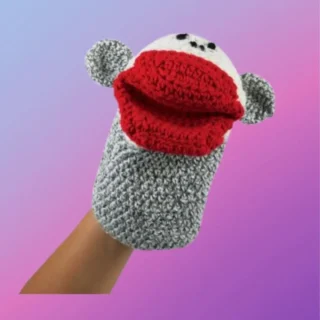 Crocheted sock monkey hand puppet with gray body, white face and large red mouth