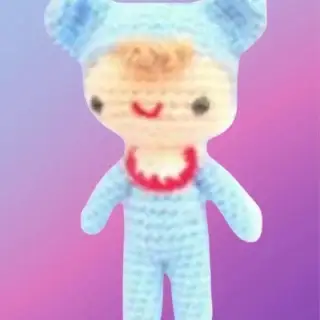 Crochet baby doll with blue outfit, yellow skirt and embroidered facial details