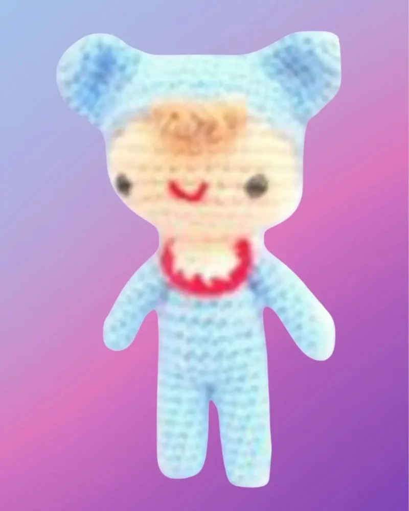 Crochet baby doll with blue outfit, yellow skirt and embroidered facial details