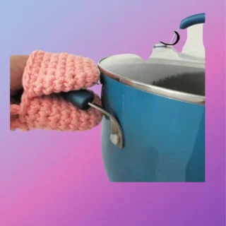 Handmade crochet mini heat mitt gripping the handle of a cooking pot