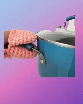 Handmade crochet mini heat mitt gripping the handle of a cooking pot