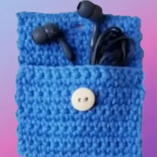 Blue crocheted mini pouch with button closure holding earbuds and cord.